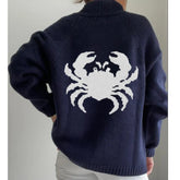Navy blue sweater with a white crab design on the back, worn by a person.